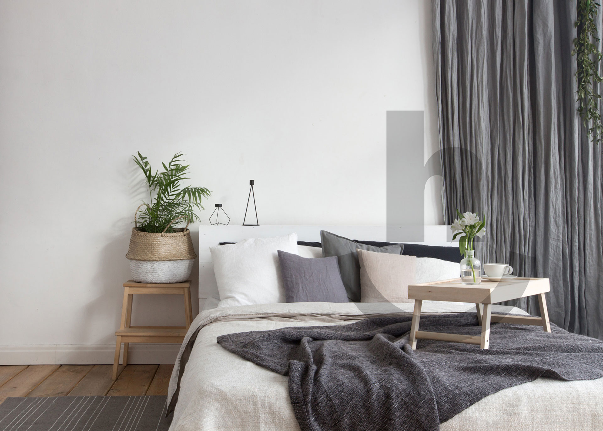 a made bed with a plant beside it in a bright modern minimalist home